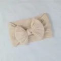 Primer plano de una diadema de punto de ochos para bebé en color crema con un lazo - Estilo de Lazo Torcido / Beige