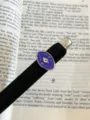 Close-up of a blue enamel evil eye celestial metal open ring displayed on a book page. - Dark Blue Evil Eye (JZ0103A)