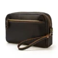 Vue détaillée du sac à poignet en cuir marron foncé avec fermetures éclair et coutures. - 9458 - Marron foncé