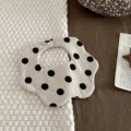 Flower-shaped cotton muslin baby bib with black polka dots on cream background. - Petal Bib / Light Grey Polka Dot