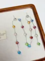 Detailed shot of long dangling earrings featuring vibrant multicolored faceted beads on fine chains. - Colorful Beaded Earrings