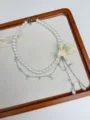Detailed close-up of layered white pearl necklace with beaded flower and rhinestone chains. - Creamy White Flower Necklace