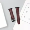 Primo piano di un cinturino in pelle rosso scuro con texture coccodrillo e fibbia nera. - 42/44/45/49 mm - (46 mm Gen 10/11) / Rosso vino - fibbia nera