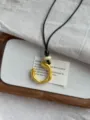 Detail view of long black cord necklace with decorative beads and gold curved pendant. - Gold Geometric Pendant Style (XL1151A)