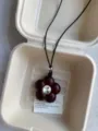 Close-up of a dark red flower pendant necklace with crystal center in a pulp box. - Brownish Red Flower Style (XL1150)