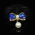 Detailed view of DIY pearl bow jewelry accessory featuring blue crystal hearts and dangling pearl. - Sapphire Blue