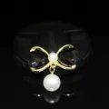 Close-up detail of a sweet bow pearl charm DIY jewelry accessory with black and gold tone. - Black