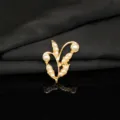 Primo piano dettagliato di spilla di perle con foglia di ramo in lega d'oro, elegante. - Perla Sintetica