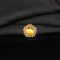 Close-up detail of a golden alloy round rhinestone button with yellow gemstone for DIY craft decor. - Yellow