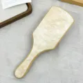 Vista detallada del cepillo de bambú con un elegante acabado de acetato de mármol crema. - Beige