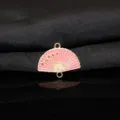 Primo piano dettaglio del ciondolo a ventaglio in smalto rosa con fiori di prugno e anelli. - Rosa