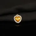 Close-up detail of yellow heart crystal pendant with rhinestones, gold tone alloy jewelry charm. - Golden Yellow