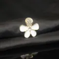 Primo piano dettagliato dell'accessorio in lega con fiore a cinque petali smalto strass. - Bianco