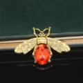 Primo piano di un ciondolo ape dorato vintage con pietra rossa brillante per lavori fai-da-te. - Ape rubino