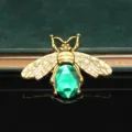Primo piano del ciondolo ape dorata vintage con gemma verde ideale per decorare cover di telefoni. - Ape Smeraldo