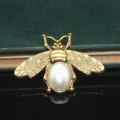Primo piano di spilla ad ape dorata con corpo in perla sintetica e ali dettagliate per fai da te. - Ape con Perla