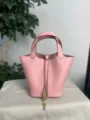 Close-up of pink leather bucket bag with lock detail, textured grain finish and gold hardware. - Gold Buckle / 3Q Pink
