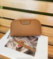 Brown genuine leather clutch wallet detail, featuring a delicate silver clover metal accent. - Caramel color