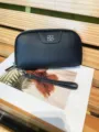 Close up of black genuine leather wristlet wallet featuring chic metal flower accent and zipper. - Black