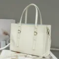 Bolso tote de cuero genuino en blanco crema en detalle, con asas dobles y hebillas metálicas. - Blanco Roto