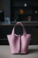 Close-up van de roze lederen emmertas met fijne textuur en het detail van het metalen slot. - L18 B13 H18 cm / 3Q roze met zilveren gesp