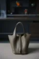Detail view of premium leather bucket tote bag with metal lock and top handles, elegant style. - L18 W13 H18 cm / Taupe Silver Buckle