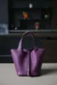 Detailopname van paarse lederen emmertas met klassiek hangslot en dubbele handgrepen. - L18 B13 H18 cm / Anemoonpaars met zilveren gesp