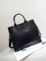 Dettaglio della borsa tote in pelle nera, finitura cerata e stile retrò per uso quotidiano. - Nero