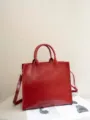 Primo piano dettagliato della borsa shopper vintage in pelle rossa con texture e manici. - Rosso