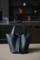 Gedetailleerd uitzicht op de donkerblauwe lederen emmertas met fijne textuur en hardware. - L18 B13 H18 cm / Middernachtblauw met zilveren gesp