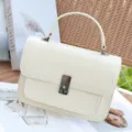 Detail shot of elegant off-white genuine leather crossbody bag with metal lock hardware. - Off White