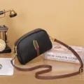 Chic women's leather dome crossbody bag with adjustable strap and stylish metal hardware. - Black