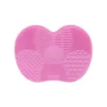 Pink silicone makeup brush cleaning mat with multiple textured zones and suction cups for use. - Pink