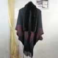 Detailed view of black knitted cape with luxurious faux fur collar and elegant fringe edges. - 1# Black