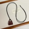 Detail view of miniature handbag pendant necklace featuring black cord on textured backdrop. - Red Bag Style (Z-4528)