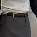 Ceinture en cuir noir classique avec boucle métallique assortie à une jupe grise mode. - Noir