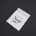 Close-up detail view of frosted clear self-sealing plastic packaging bag with custom print text. - 10x10+3cm (20 Pieces/Pack)