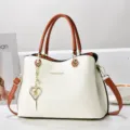 Vue détaillée d'un sac cabas bicolore élégant avec charm cœur et finitions dorées brillantes. - Patchwork Blanc et Jaune