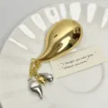Detail view of the French retro metal teardrop chili brooch with chic dangling tassels. - Gold