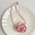 Detail shot of a pink fabric rose choker necklace on white plate, sweet vintage style detail. - Rose Choker (Z-1065) / Pink