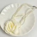 Dettaglio in primo piano della collana di perle multistrato con grande ciondolo, gioiello. - Beige
