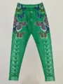 Close-up detail of green women's leggings featuring vibrant butterfly print and unique lace-up pattern. - S / Green