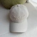 Vista detallada de la gorra de béisbol beis lavada con elegante bordado en la parte delantera. - Gris claro
