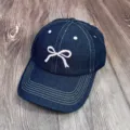 Détail en gros plan de la casquette de baseball en jean bleu foncé avec broderie nœud rose. - Taille Unique Adulte Réglable / Bleu denim - nœud rose
