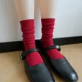 Detail shot of red ribbed mid-tube slouch cotton socks paired with black shoes for women. - One Size / Vertical Stripes - New Year Red