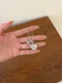 Detailed close-up of a sparkling zirconia cross and pink heart pendant necklace on a hand. - Pink Heart Cross Style (XL5193)