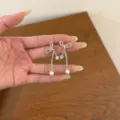 Close-up detail of sparkling rhinestone bow earrings with cute heart and pearl pendants. - Silver Bow Tassel Pearl Style (EH3243)