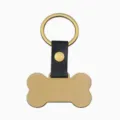 Vue de détail en gros plan d'une étiquette pour animal en métal doré avec lanière en cuir. - Cuir Os Or
