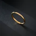 Gros plan détaillé d'un anneau minimaliste en acier plaqué or 18k avec trois petites pierres zircones. - Taille 5 / Trois Pierres / Or