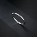 Gros plan d'un anneau en métal argenté minimaliste orné de trois petites pierres de zircone scintillantes. - Taille 5 / Trois Pierres / Acier